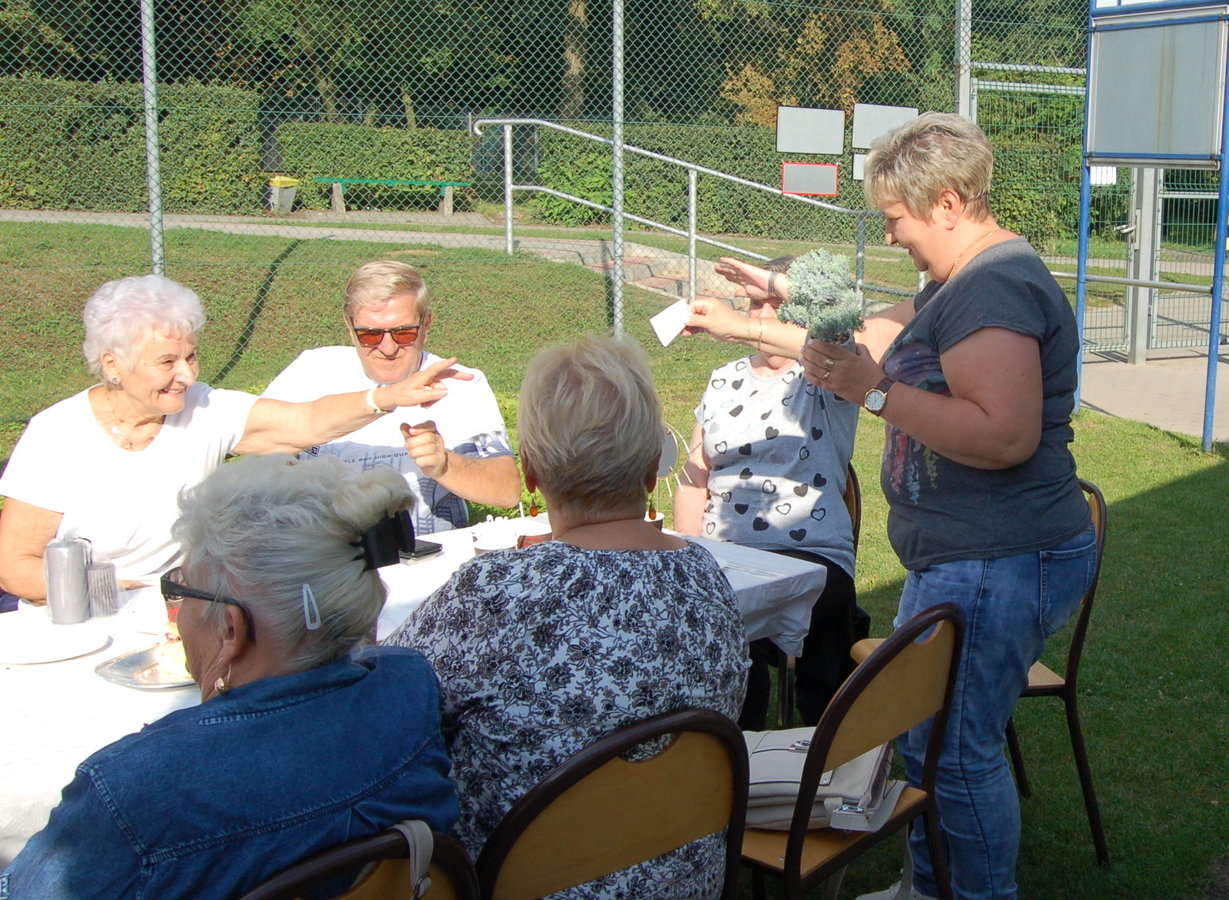 seniorzy siedzący przy stole podczas losowania upominków