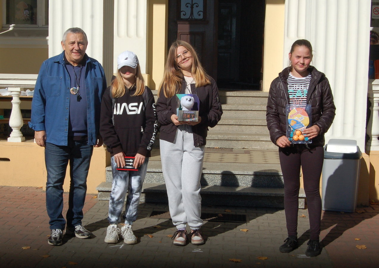 kierownik Ośrodka wraz z nagrodzonymi dziećmi i młodzieżą na tle wejścia do szkoły w Bronikowie